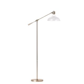A brass floor lamp with a glass shade