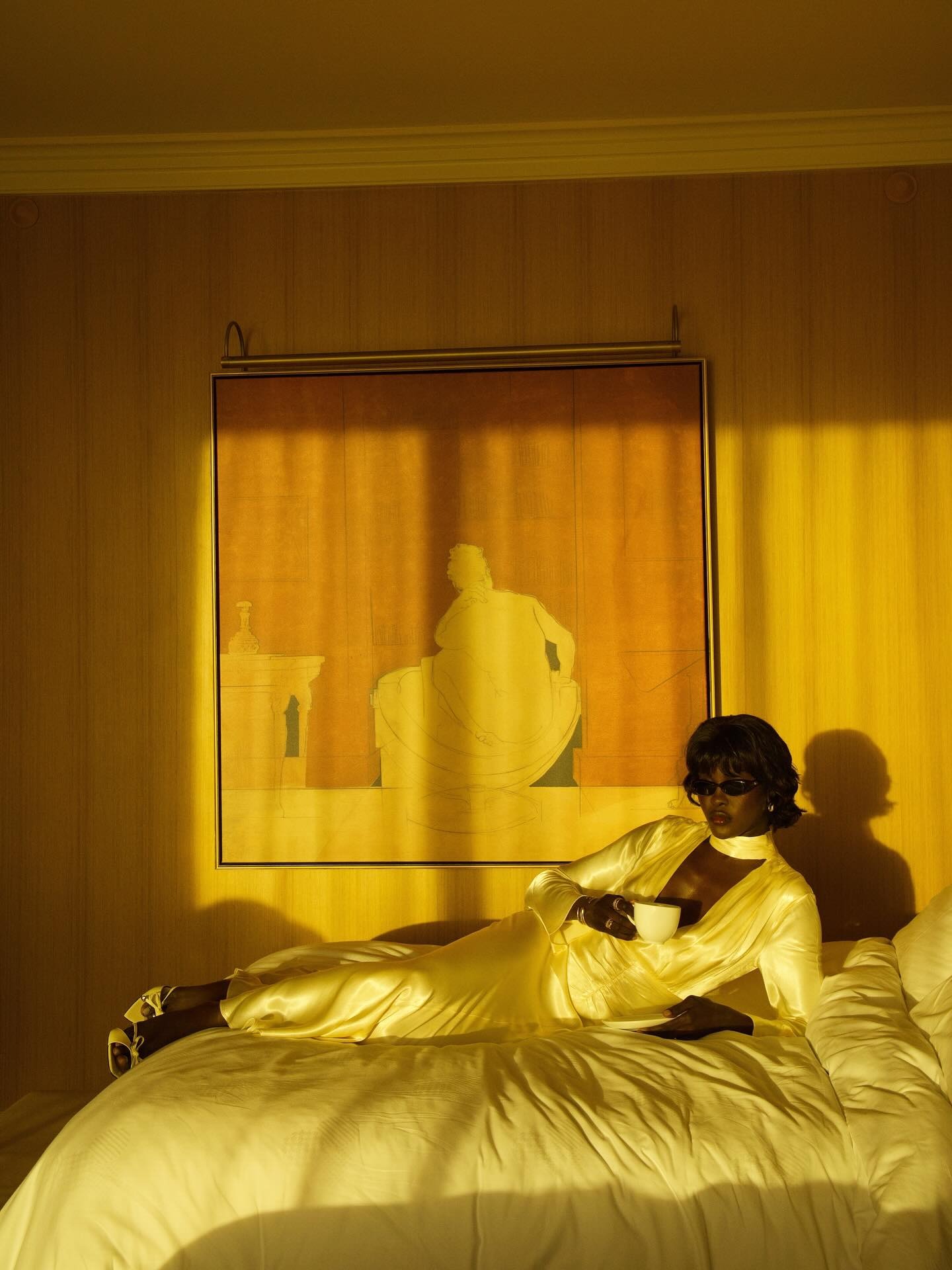 Influencer @lefevrediary lays on a bed wearing a white satin scarf dress.