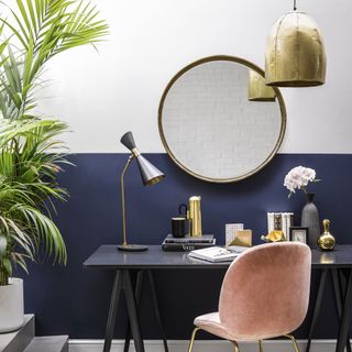 Home office with blue and white walls, round mirror, desk lamp and pendant light
