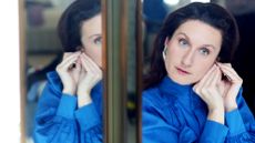 Woman in a blue shirt photographed looking in a mirror