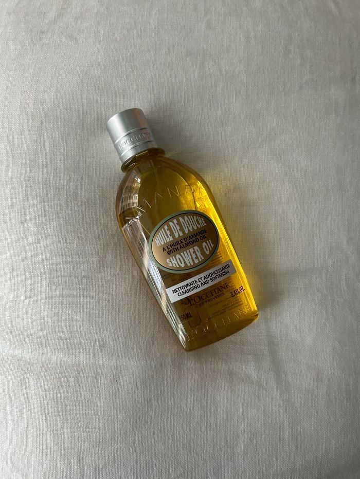 A picture of the L'Occitane Almond Shower Oil on a white linen background