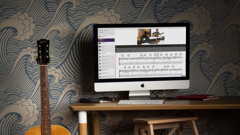 Acoustic guitar sat next to a computer displaying a TrueFire lesson