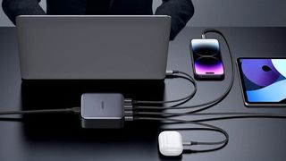 Man using Ugreen Nexode 100W USB C Wall Charger to charge his MacBook, phone and tablet simultaneously