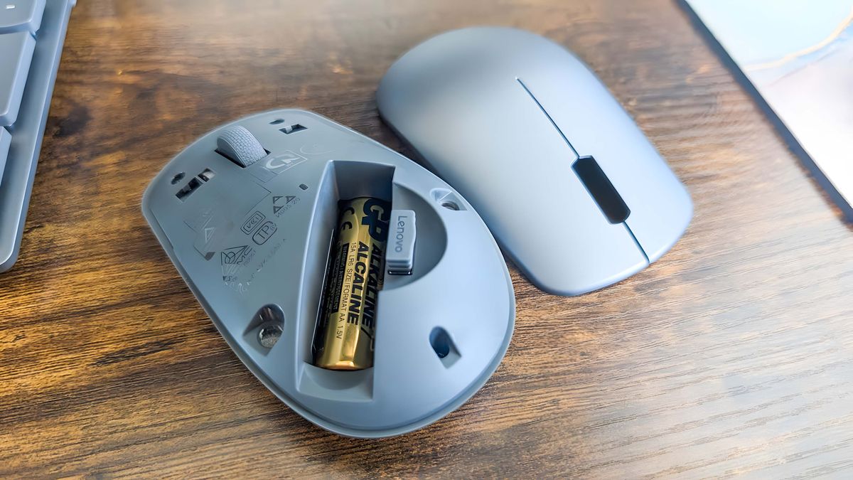The mouse with the top removed to reveal the battery slot and the USB-A dongle storage area.