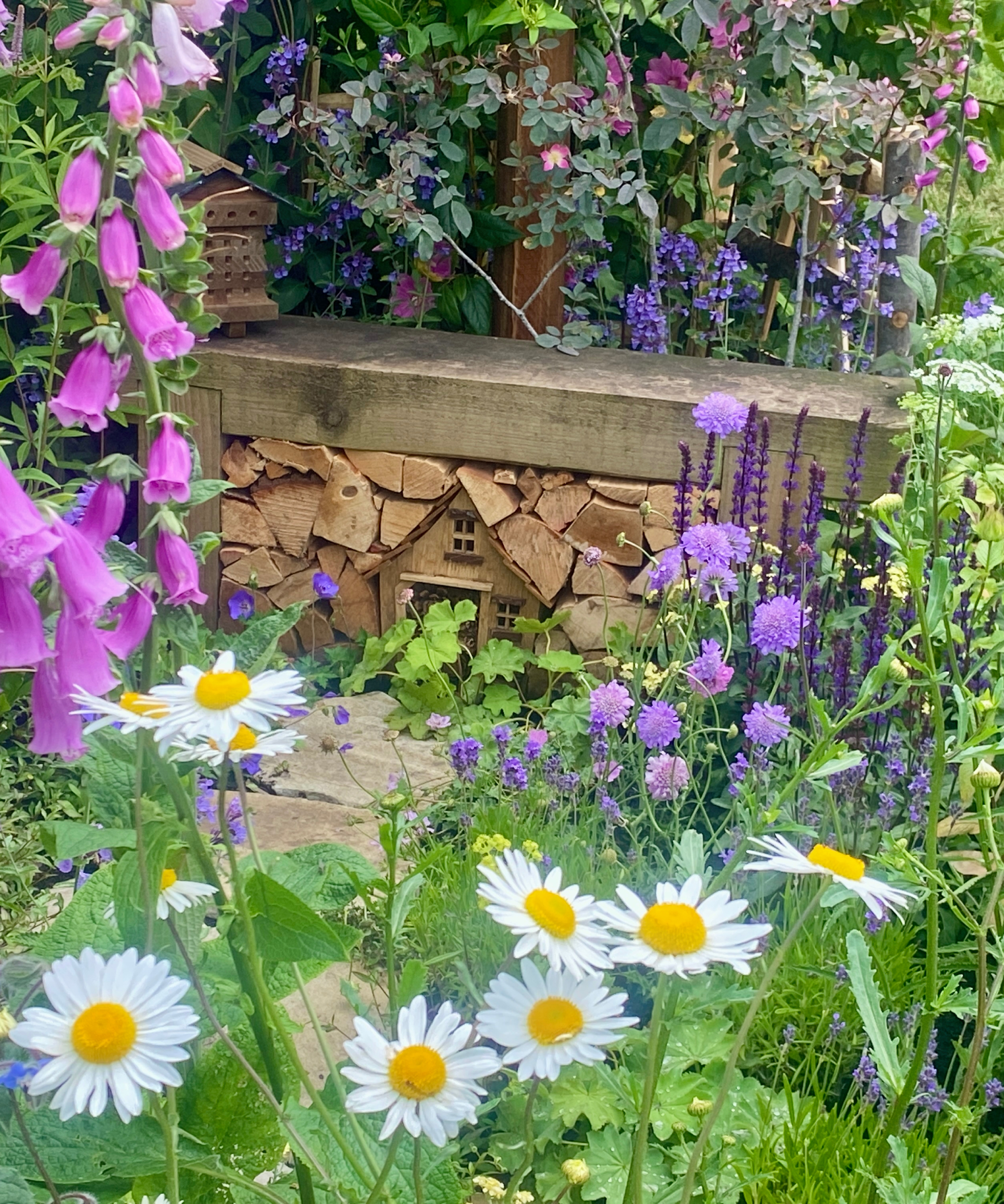 insect hotel made of logs under a garden bench