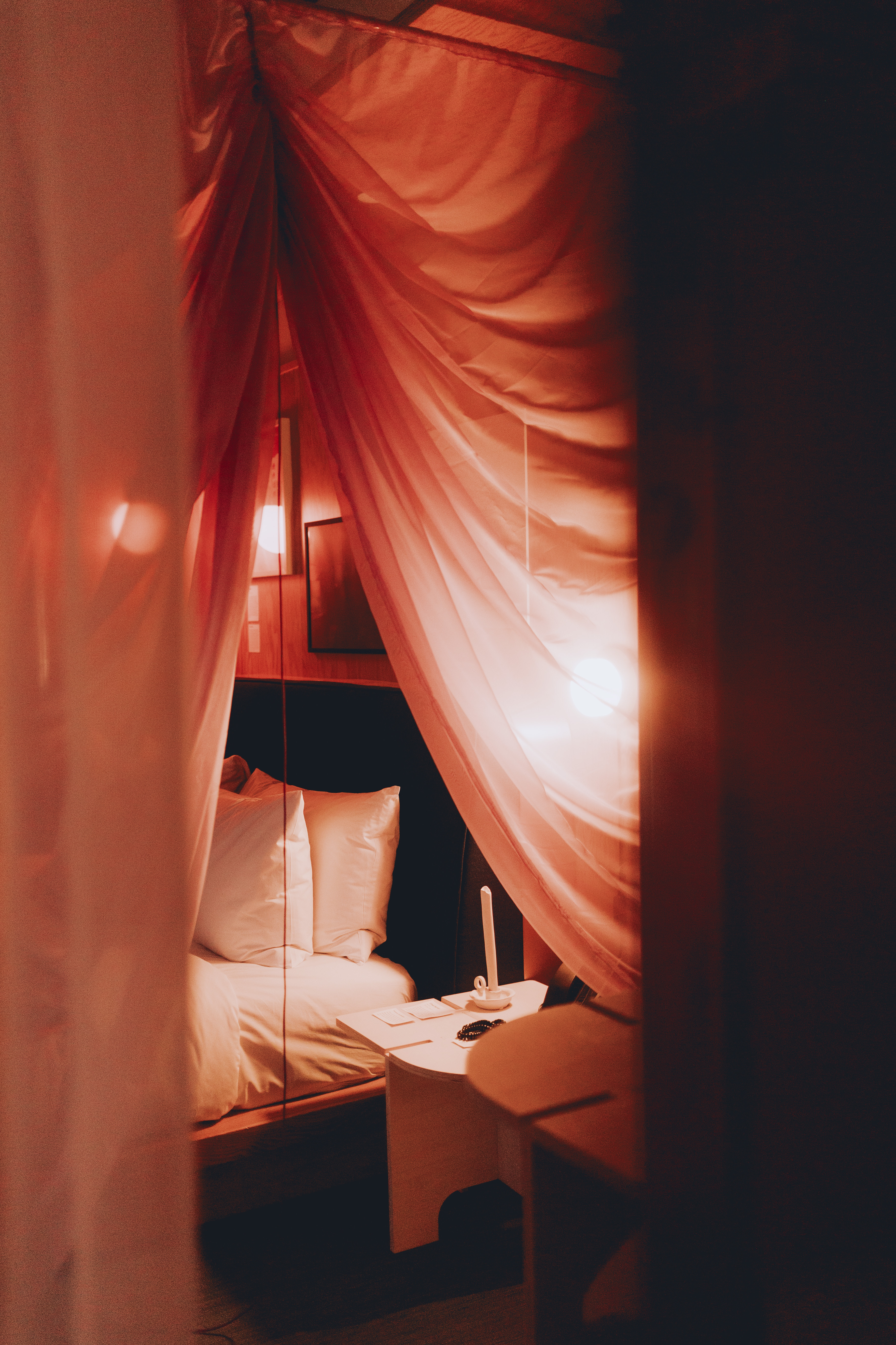 softly lit bedroom shrouded with draped pink curtains