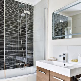 Bathroom with over-shower bath and black wall tiles