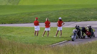 Women wearing red playing golf at Marco Simone Golf Club ahead of the Solheim Cup in 2023