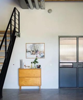 Entryway with wooden sideboard and black metal staircase