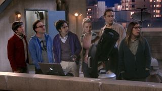 Howard, Leonard, Raj, Penny, Sheldon and Amy standing on the roof of their apartment building in front of an open laptop and a telescope, with everyone looking off-camera at Staurt