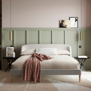 A bedroom with pale green panelling half way up the walls and a curved cream bedframe