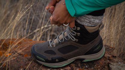 Woman lacing up a Vasque Breeze AT Mid GTX hiking boot