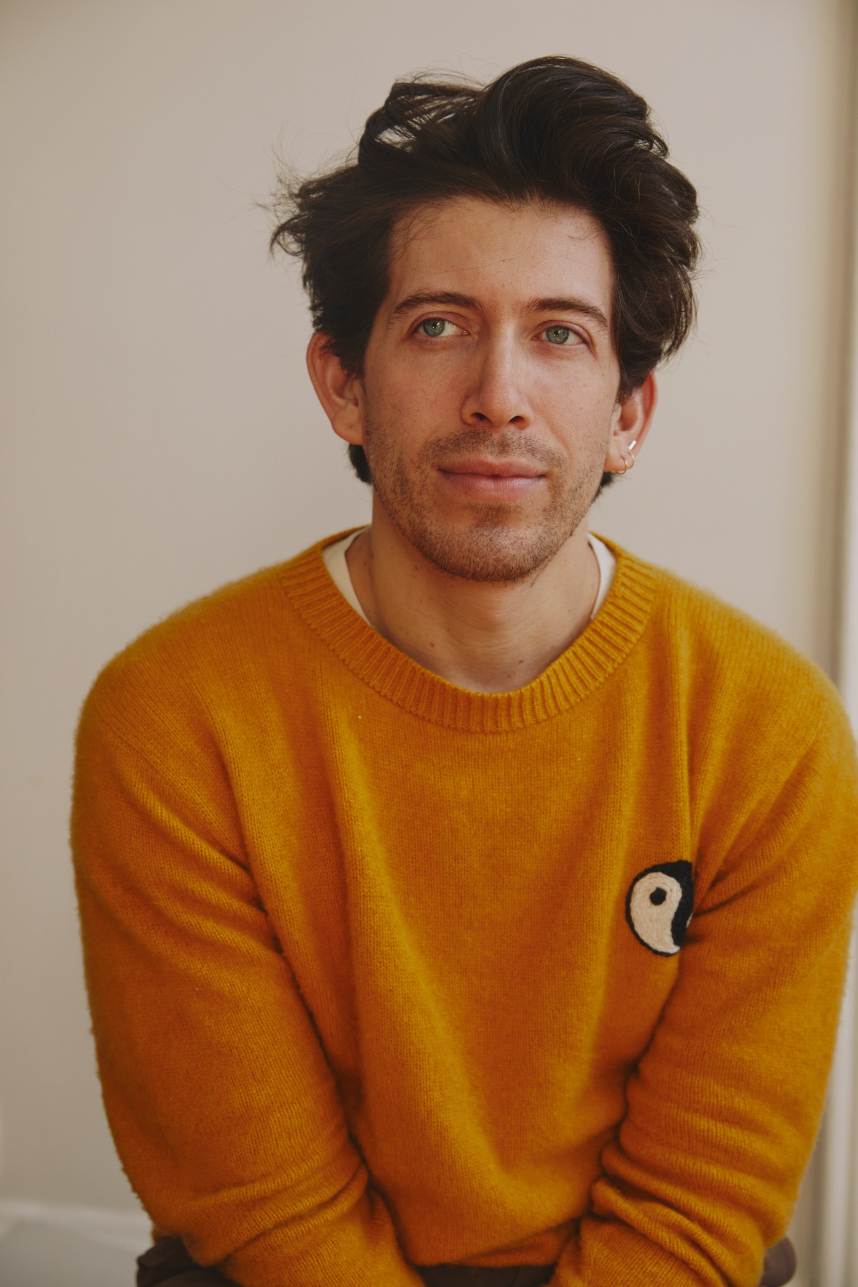 a white man with dark brown hair in a yellow sweater