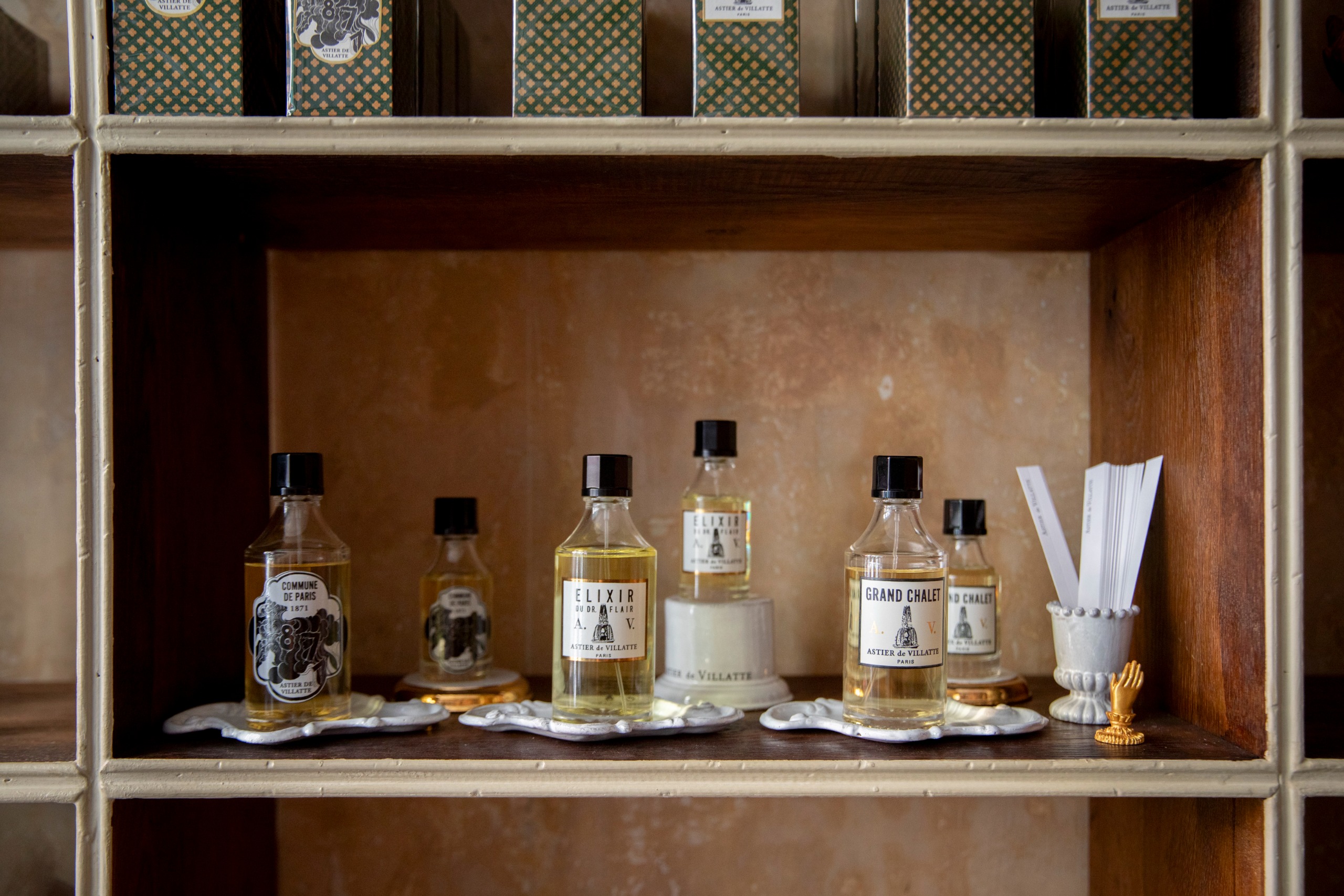 Interiors of an Art Deco-inspired parfumerie and stationery shops, with stacked-up wooden shelving, an earthy palette, and a stuck-in-time atmosphere with bespoke packaging.