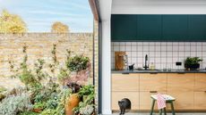 Modern kitchen with bifold doors leading into a garden space. A cat is peeking out of the build in 'nap nook' in the lower kitchen cabinets.