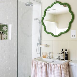 Bathroom with curtain underneath sink and wavy green mirror