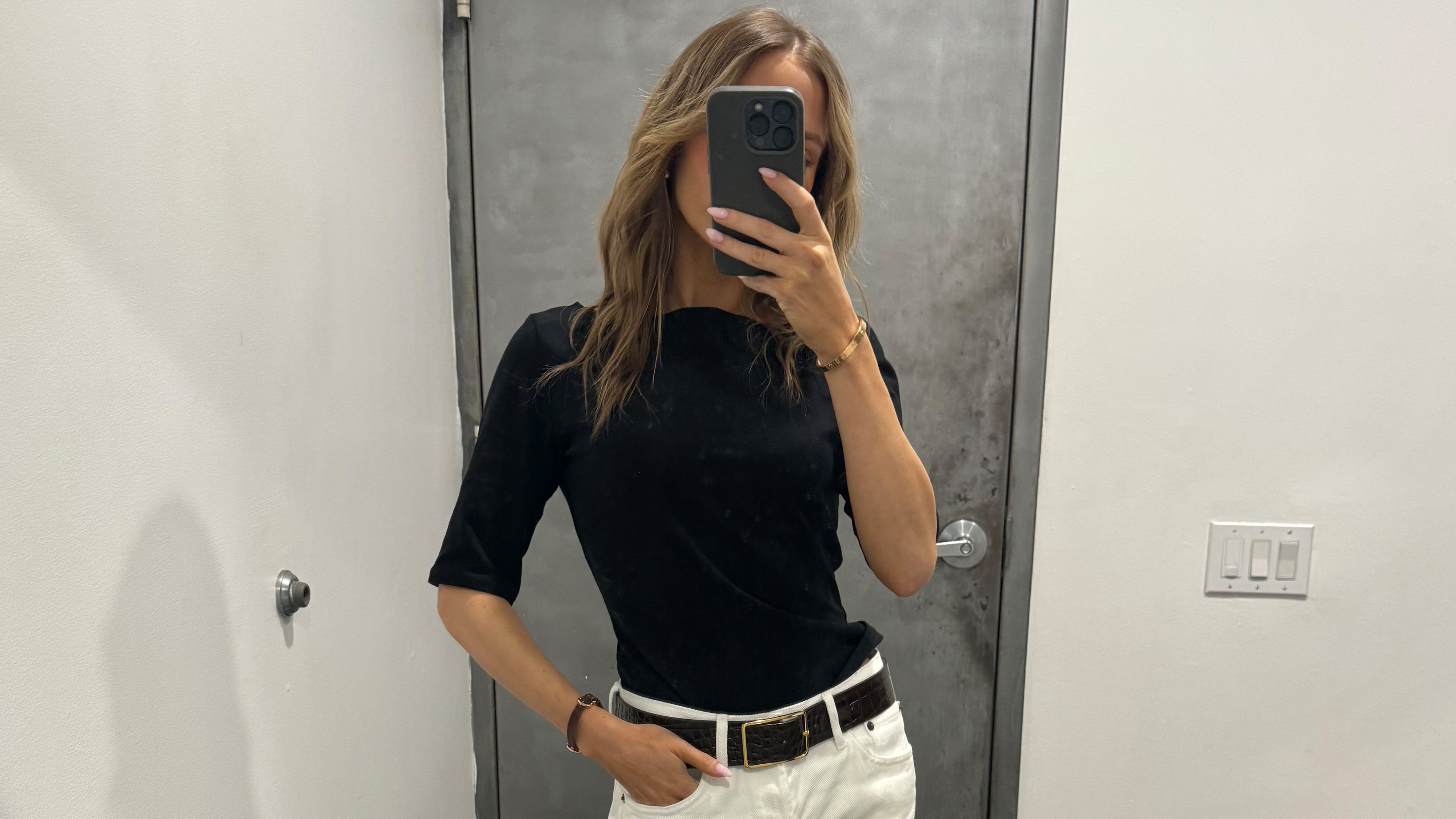 Nikki wears a black tee and white jeans.