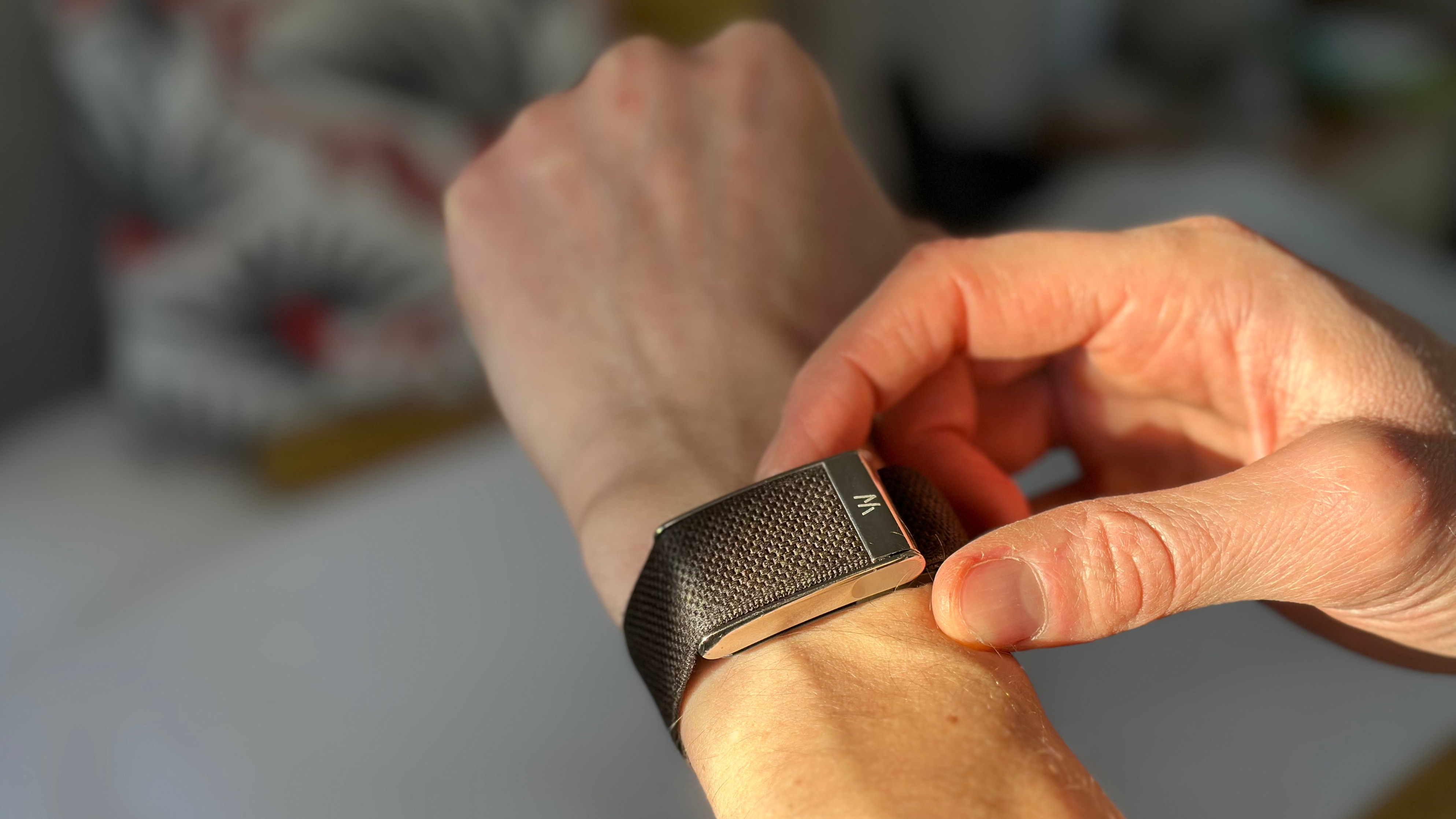 Fitness writer Sam Rider wears the Whoop Band 5.0 on his left wrist, adjusting it with his right hand.