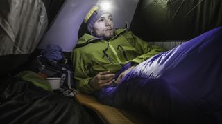A man inside his sleeping bag in his tent