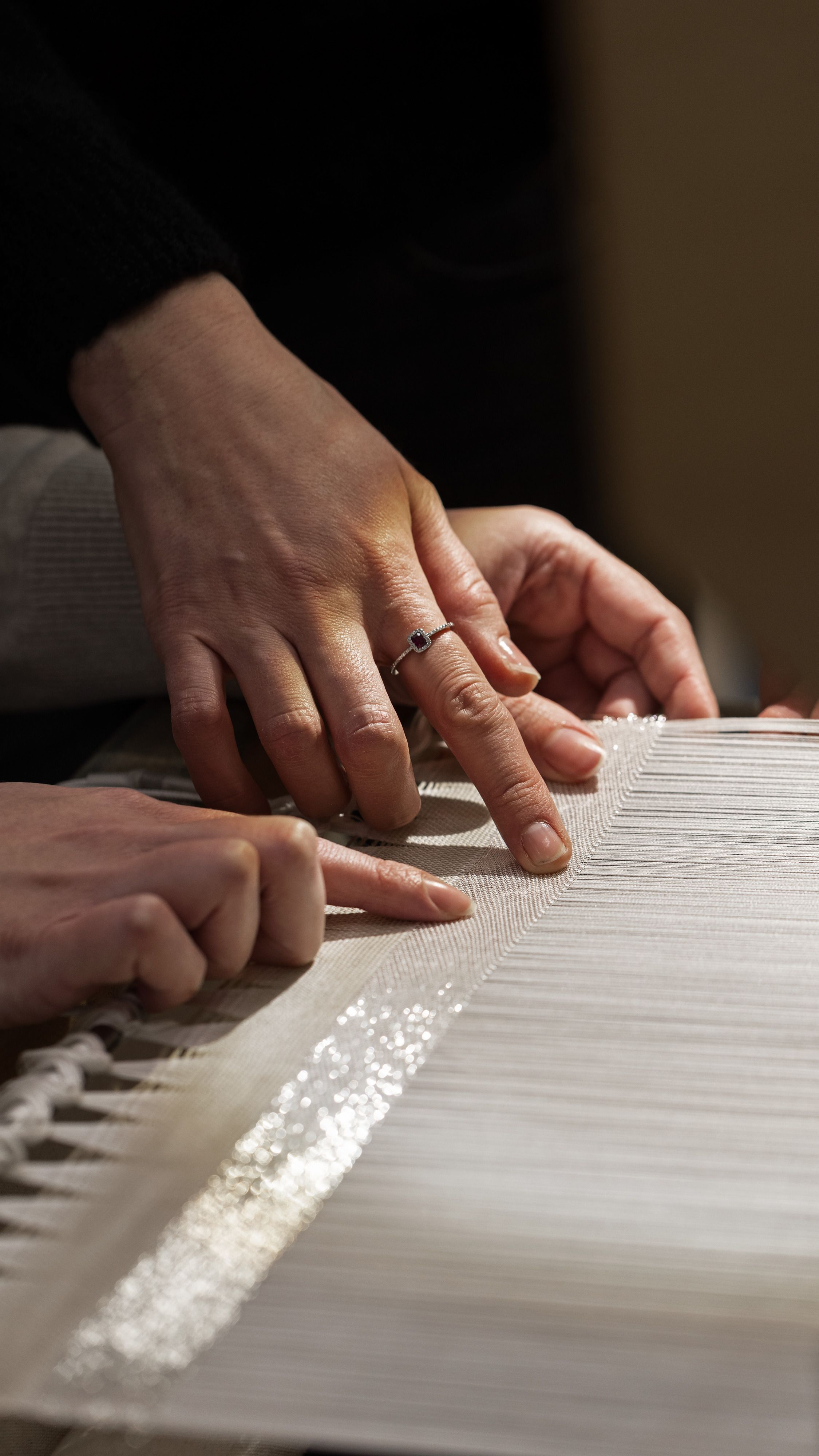 Close-ups of artisanal works in textile and polished stone, and a portrait of two artisans, a man and a woman, sitting in front of a gradient fabric panel in tints of green, blue, orange, and white.