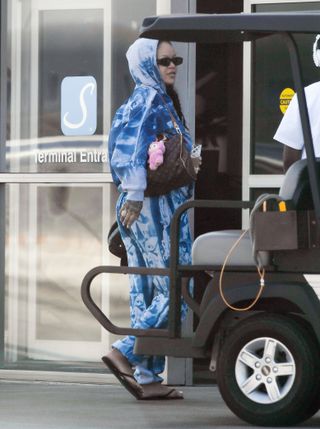 Photo of Rihanna walking in tie-dye sweat-set wearing Louis Vuitton bag and pink labubu plushie bag charm.