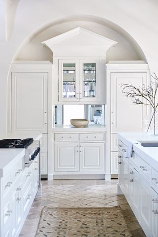 white kitchen with beautiful architecture and cabinetry and rug on floor