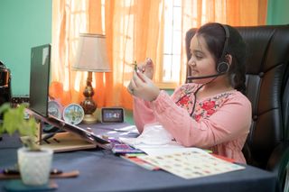 A young student learns while sitting in front of a laptop.