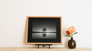 The new Galari digital art frame, on a small stand, sat next to an orange flower. 