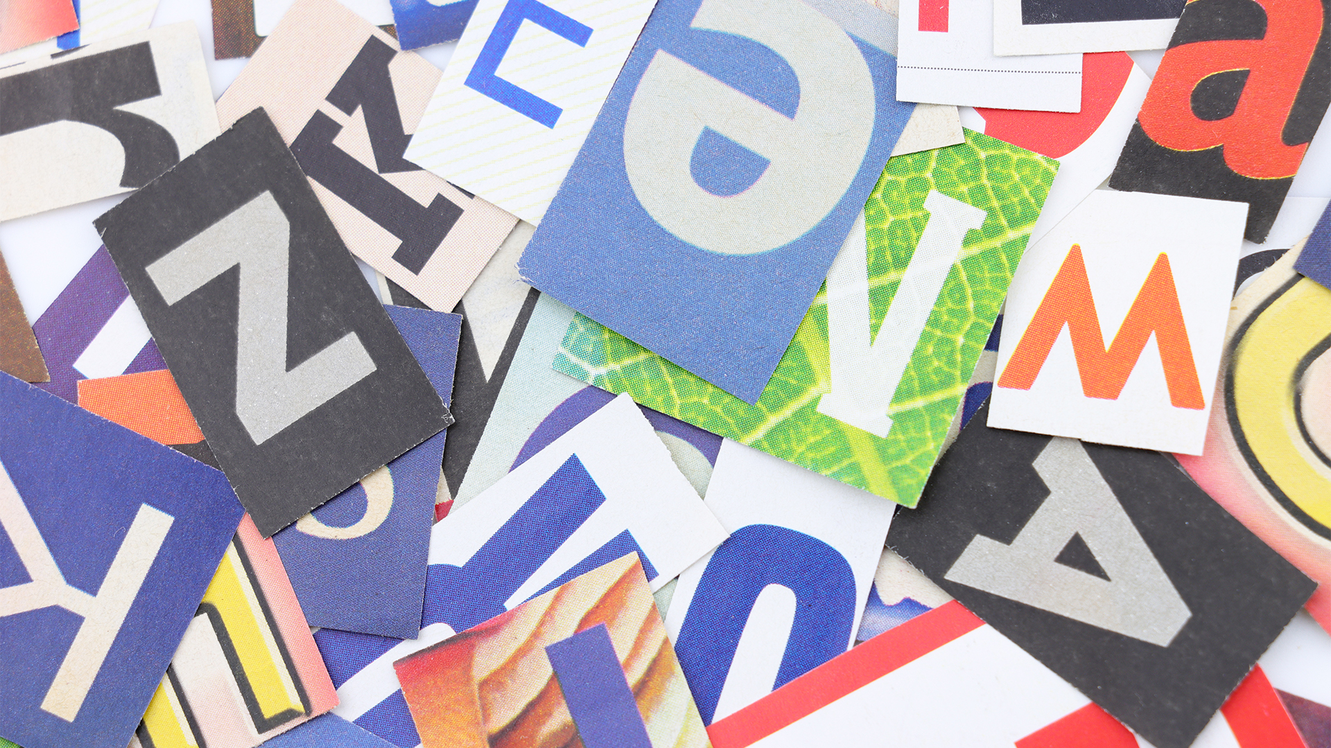 Assorted coloured newspaper print style letters overlapping 