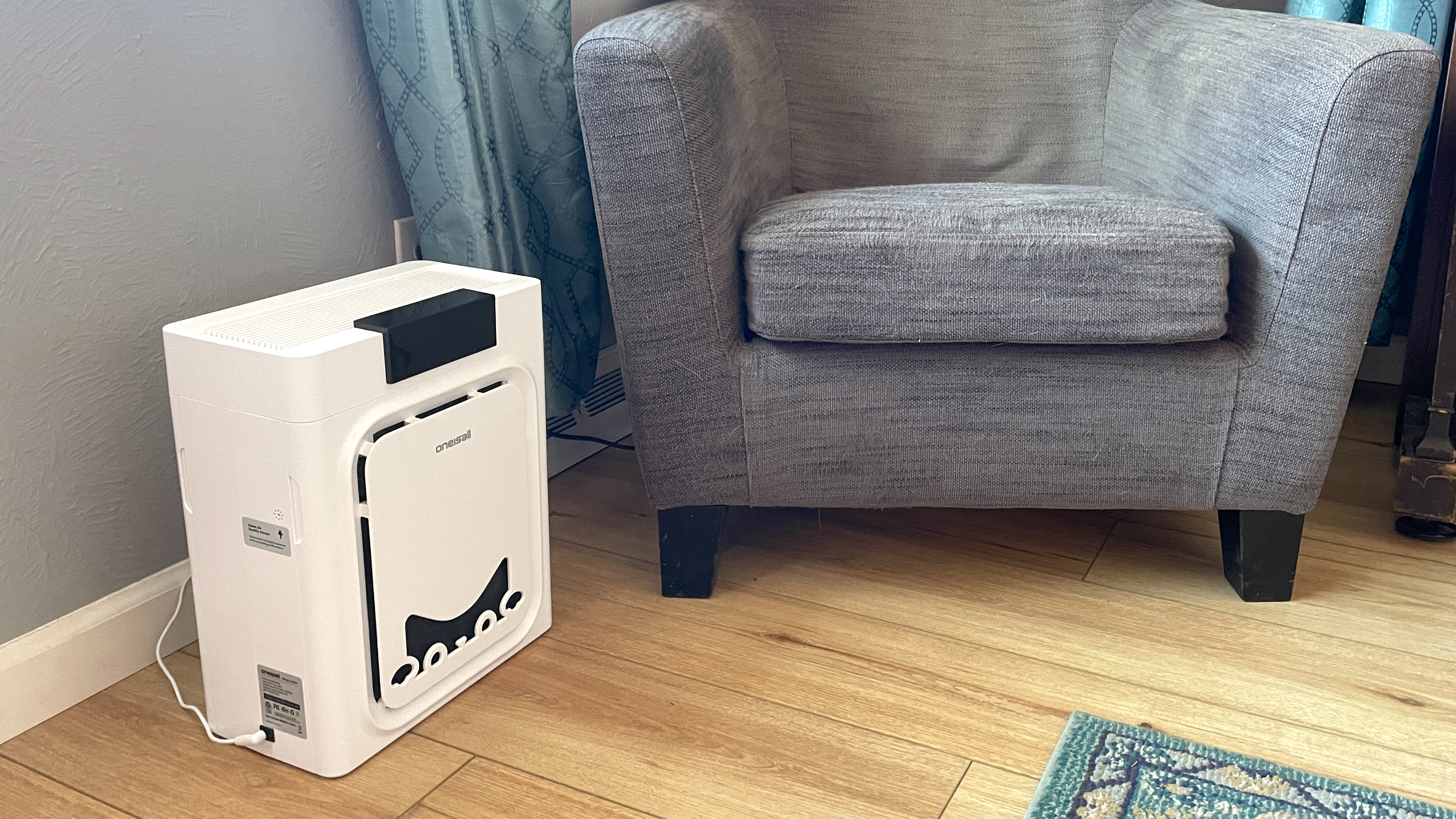 Oneisall air purifier in living room next to grey armchair