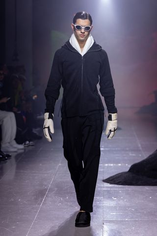 Model on runway in black ski jacket and trousers by Saul Nash