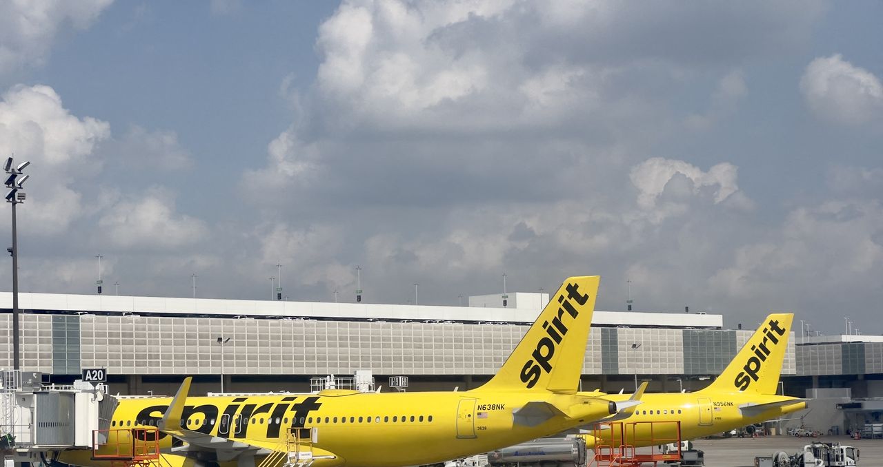 Yellow Spirit Airlines planes sit at airport gate.