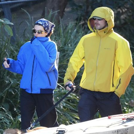 Kendall Jenner and Jacob Elordi walk a dog outside wearing technical jackets in blue and yellow. Kendall wears a bandana on her head and the two shield their eyes with sunglasses.