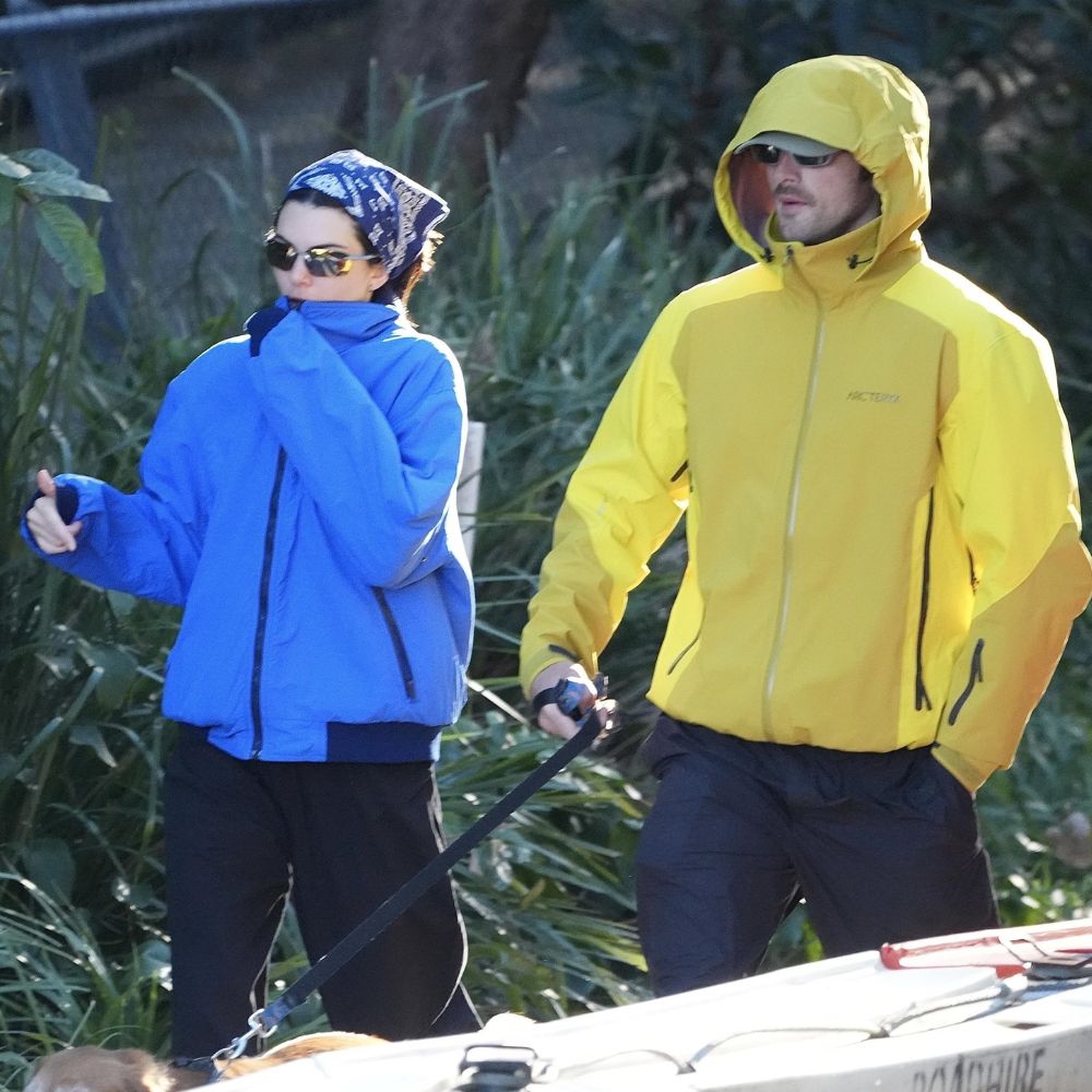 Kendall Jenner and Jacob Elordi walk a dog outside wearing technical jackets in blue and yellow. Kendall wears a bandana on her head and the two shield their eyes with sunglasses.