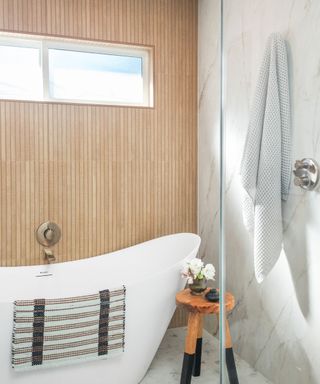 freestanding bath with wooden paneling behind