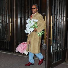 ASAP Rocky seen holding a car seat with pink blanket over it and bouquet of flowers