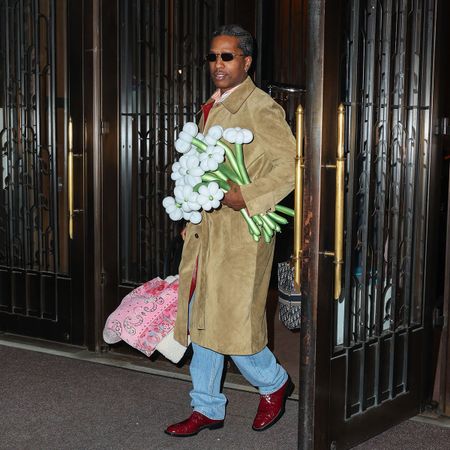 ASAP Rocky seen holding a car seat with pink blanket over it and bouquet of flowers