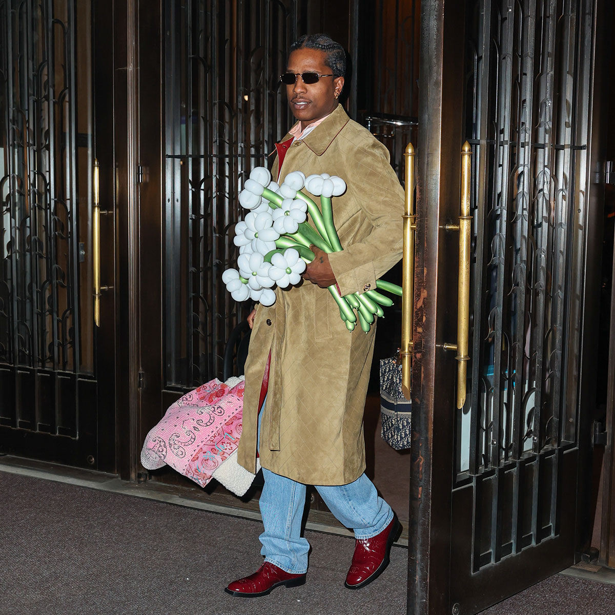 ASAP Rocky seen holding a car seat with pink blanket over it and bouquet of flowers