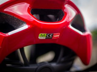 A red Kask Utopia Y aero helmet sits on a wooden bench