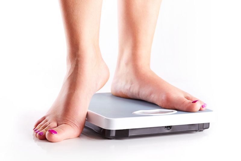 A woman stands on a bathroom scale.