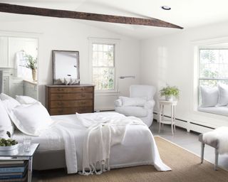 bedroom with white walls, wooden dresser and wooden ceiling beam
