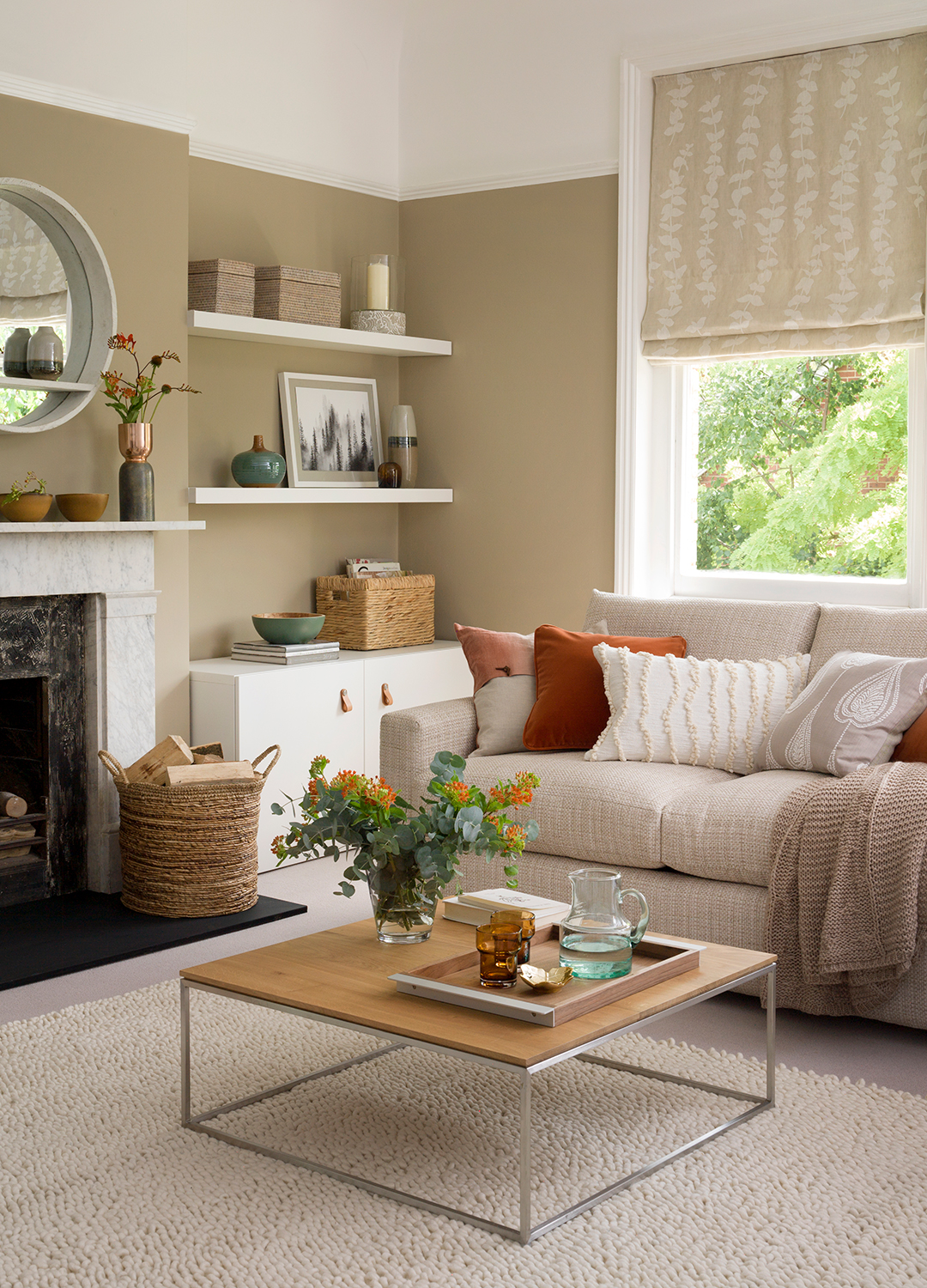 Beige living room with wood and metal square coffee table and cream sofa with autumnal layers of throws and cushions