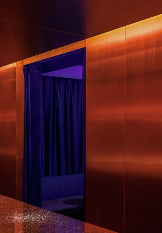 A chrome room features contrasting orange and purple lighting in a dramatic effect.