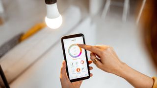 Controlling light bulb temperature and intensity with a smartphone application. Concept of a smart home and managing light with mobile devices