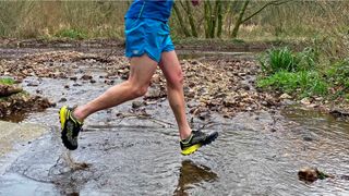 Man wearing inov-8 Mudtalon Speed trail running shoes running in water