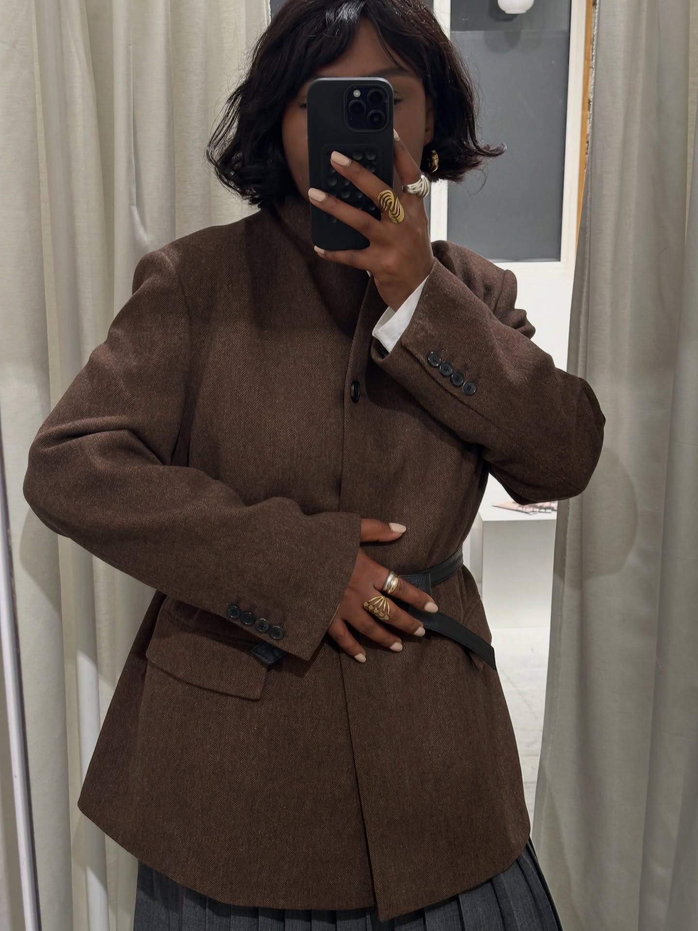 A photo of @frannfyne taking a selfie in a mirror, wearing a brown blazer and her nails painted in a milky white shade