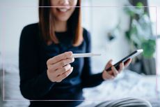 woman holding phone and pregnancy test in her hands