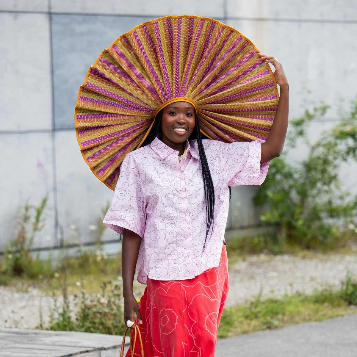 A guest wears oversized hat, pink blouse, red skirt outside Marimekko during Copenhagen Fashion Week day four on August 07, 2025 in Copenhagen,