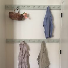 A DIY peg rail used as an alternative to a chair covered in clothes