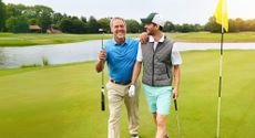Two golfers smiling while walking off the green